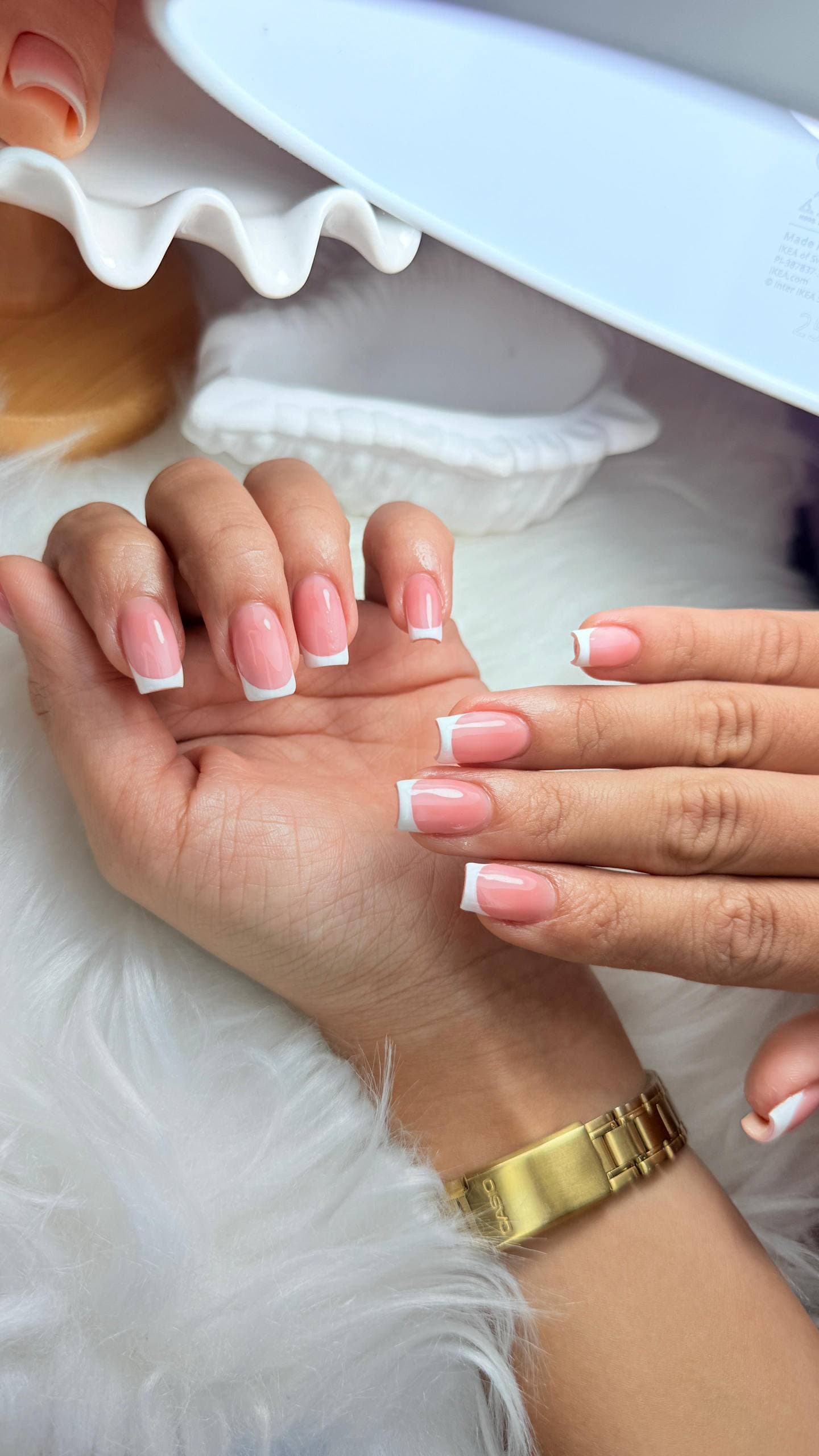 French manicure under the lamp on white fur
